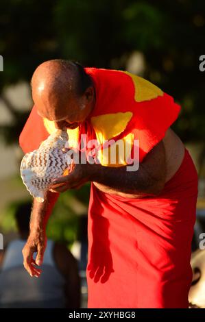 Ein Ältester fliegt bei Sonnenuntergang in eine große Muschelschale, die eine Tradition am Waikiki Beach, Hawaii, fortsetzt Stockfoto