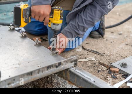 Nahaufnahme des Arbeiters Akkublockkopf verwenden Spannmutter Abdeckgrube im Wasseraufbereitungsteich festziehen. Stockfoto