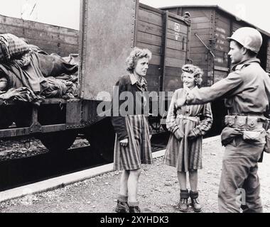 Zwei freigelassene jüdische Mädchen, die mit einem amerikanischen Soldaten im Todeszug in Dachau reden. Der Todeszug Dachau bestand aus fast vierzig Triebwagen mit 5000 Gefangenen, die am 7. April 1945 aus Buchenwald evakuiert wurden. Der Zug kam am Nachmittag des 28. April mit den Leichen von 2.000 bis 3.000 Gefangenen in Dachau an, die während der Reise ums Leben gekommen waren. Der Zug mit den Leichen wurde von der US-Armee gefunden, als er am nächsten Tag freigelassen wurde. Obwohl es ein Zwangsarbeitslager war und es dort keine Gaskammern gab, waren Brutalität und gewalttätige Strafen die Norm. Es gab 32000 dokumentierte dea Stockfoto