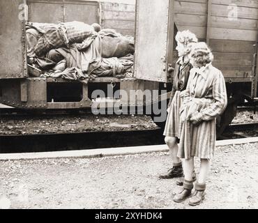 Zwei freigelassene jüdische Mädchen, die die Leichen im Todeszug Dachau anschauen. Der Todeszug Dachau bestand aus fast vierzig Triebwagen mit 5000 Gefangenen, die am 7. April 1945 aus Buchenwald evakuiert wurden. Der Zug kam am Nachmittag des 28. April mit den Leichen von 2.000 bis 3.000 Gefangenen in Dachau an, die während der Reise ums Leben gekommen waren. Der Zug mit den Leichen wurde von der US-Armee gefunden, als er am nächsten Tag freigelassen wurde. Obwohl es ein Zwangsarbeitslager war und es dort keine Gaskammern gab, waren Brutalität und gewalttätige Strafen die Norm. Dort gab es 32000 dokumentierte Todesfälle Stockfoto