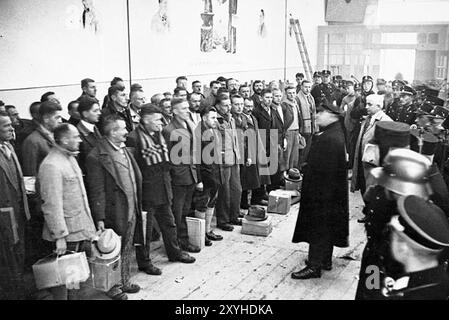 Der Lagerkommandant hält eine Rede vor Gefangenen, die kurz vor der Freilassung stehen, als Teil einer Begnadigungsaktion nahe Weihnachten 1933. Dieses Dachau war das erste Konzentrationslager der nazis, das am 22. März 1933 eröffnet wurde (nur sieben Wochen nach der Machtergreifung Hitlers). Obwohl es ein Zwangsarbeitslager war und es dort keine Gaskammern gab, waren Brutalität und gewalttätige Strafen die Norm. Dort gab es 32000 dokumentierte Todesfälle und viele Tausende weitere undokumentierte Todesfälle. Das Hauptlager (Dachau hatte 100 Unterlager) wurde am 29. April 1945 von der US-Armee befreit. Das Foto stammt vom 4. Mai 1945, fünf Tage nach der Befreiung. Stockfoto