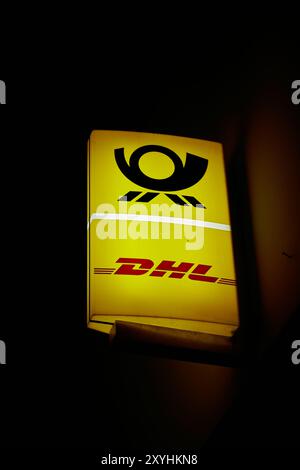 Leuchtschild eines Postamtes des deutschen Logistikunternehmens DHL in Berlin am Abend Stockfoto