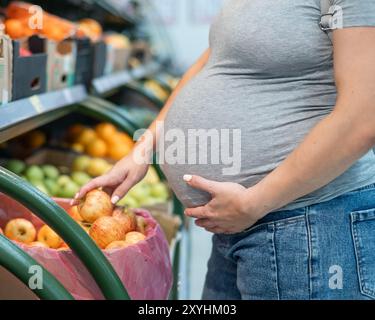 Schwangere Frau wählt Äpfel im Laden. Stockfoto