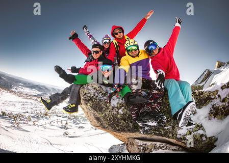 Eine große Gruppe glücklicher junger Freunde sitzt am Big Rock und hat Spaß. Konzept für Skigebiete oder Winterurlaube Stockfoto