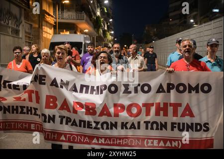 Athen, Griechenland. August 2024. Demonstranten marschieren mit einem Banner mit der Aufschrift „stoppt die Grausamkeit der Regierung der Banken und der Fonds“ während eines Protests gegen eine Vertreibung der Familie aus ihrem Haus aufgrund von Zwangsvollstreckungen. Die Demonstranten beschuldigen die Banken, die Gelder und die griechische Regierung für Grausamkeit, da sie behaupten, dass die Familie, die ihre Hypothek nicht zurückzahlen kann, ein behindertes Kind habe. Das Land steht vor einem sich verschärfenden Wohnungsmangel, der zu einem ernsten sozialen Problem geworden ist und für normale Haushalte äußerst unerschwinglich ist. Quelle: Dimitris Aspiotis/Alamy Live News Stockfoto