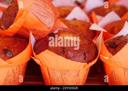 Genießen Sie den verführerischen Geschmack frisch gebackener Muffins in leuchtenden Orangenpackungen Stockfoto
