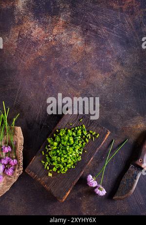 Grüne Schnittlauch oder allium in Blüte mit violetten, violetten Blumen und grünen Stielen auf einem Holztisch ist Schnittlauch ein essbares Kraut für die Küche. Stockfoto