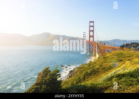 Sonnenlicht sorgt für Höhepunkte, Linsentötungen über Marin Headlands mit Golden Gate Bridge, die während Sonnenuntergang über der felsigen Küste von Fort Point zu sehen ist Stockfoto