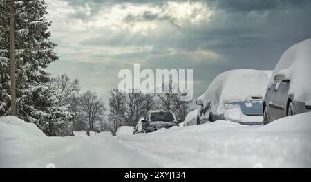 Bezaubernde Winterlandschaft, in der eine Gruppe von Fahrzeugen von einer frischen Schneeschicht bedeckt ist, die auf einen Wintersturm oder einen Schneesturm hinweist Stockfoto