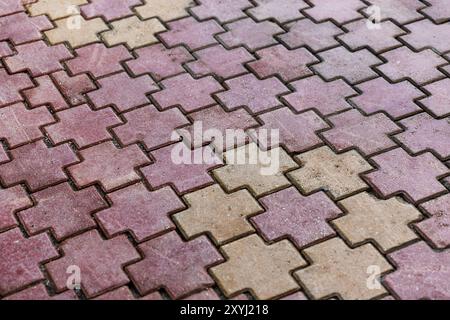 Hintergrundfoto mit Kopfsteinpflaster, geometrisches Muster aus roten und gelben kreuzförmigen Betonblöcken Stockfoto