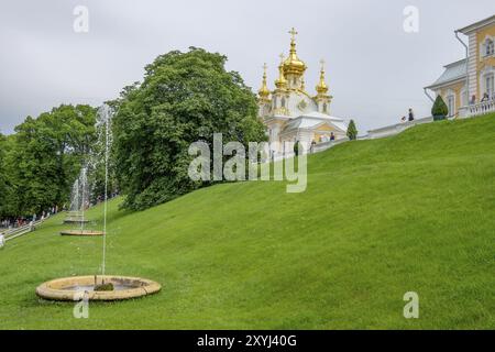 Großer Garten mit Brunnen und Kirche im Hintergrund, sankt petersburg, ostsee, russland Stockfoto