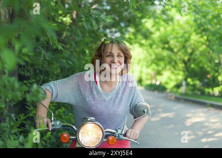 Frau mittleren Alters, Motorroller entlang der Landstraße Stockfoto