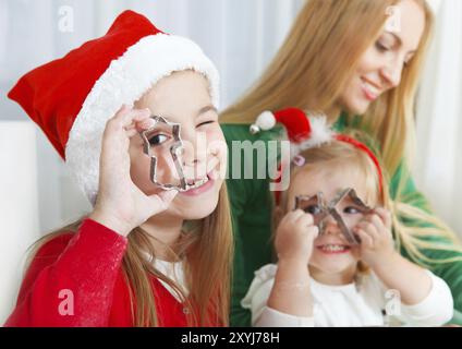 Zwei kleine Mädchen mit Mutter Backen Weihnachtsplätzchen in der Küche Stockfoto