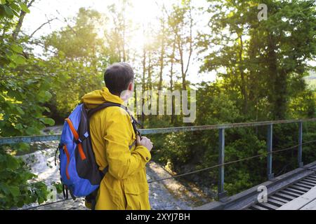 Tourist-Mann zu Fuß über Holzbrücke über Bergfluss Stockfoto