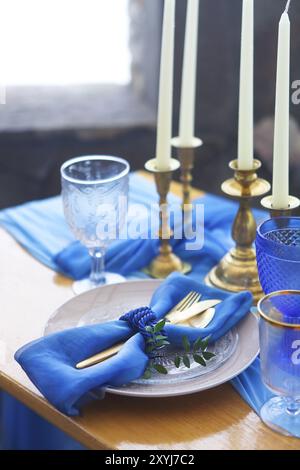 Tischdekoration im Vintage-Stil ist mit Kerzen in goldenen und blauen Farben dekoriert. Stockfoto