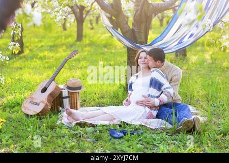 Schwangere paar im blühenden Garten beim Picknick. Zeit zum Faulenzen Stockfoto