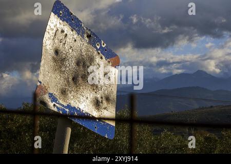 Ein rostiges, zerrissenes Straßenschild vor einer bergigen Landschaft unter einem bewölkten Himmel, Lefka Ori, White Mountains, Bergmassiv, Westen, Kreta, Griechenland, Stockfoto