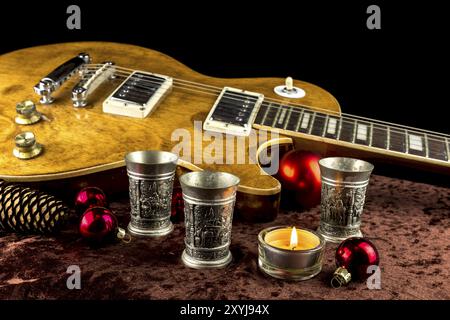 Elektrische Gitarre mit Becher und Kerze für Weihnachten dekoriert Stockfoto