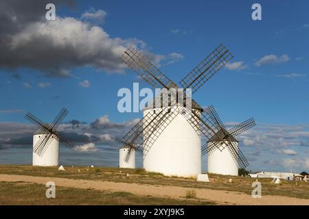 Weiße Windmühlen unter einem klaren blauen Himmel mit verstreuten Wolken. Die Umgebung ist hell beleuchtet und zeigt eine sonnige Atmosphäre, Windmühlen, Campo de cript Stockfoto