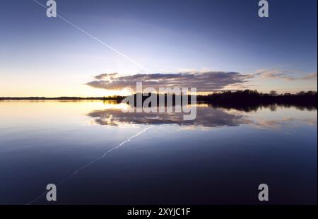 Symmetrie der Reflexion des Himmels während des Sonnenuntergangs im See Stockfoto