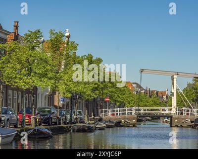 Ruhige Kanallandschaft mit Zugbrücke, Autos am Ufer und grünen Bäumen unter blauem Himmel, alkmaar, niederlande Stockfoto