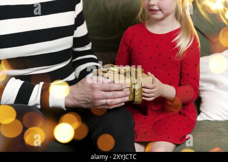 Frohe Weihnachten und Frohes neues Jahr. Weihnachtsgeschenk Überraschung. Kleine Tochter Mädchen erhält Weihnachtsgeschenk in Staunen. Der Vater gibt seine Tochter Stockfoto