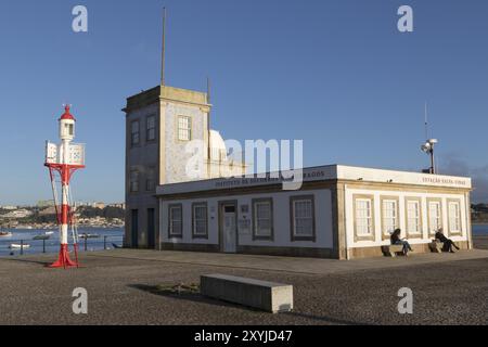 Leuchtturm Farolim da Cantareira vor der historischen Fassade der Capela-Farol de Sao Miguel-o-Anjo im Abendlicht an der Strandpromenade Stockfoto