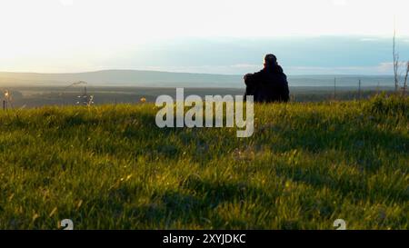 Eine Person genießt friedlich den atemberaubenden Sonnenuntergang in der Natur mit Panoramablick Stockfoto