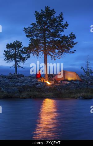 Mann sitzt am Lagerfeuer neben seinem Zelt, Norrbotten, Lappland, Schweden, August 2012, Europa Stockfoto