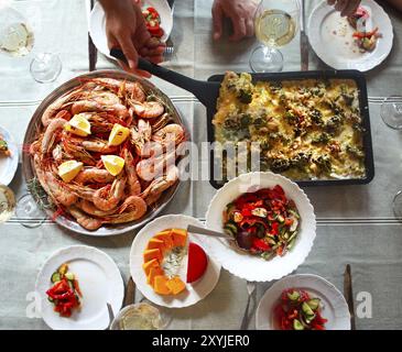 Die Ansicht von Oben auf einem Tisch mit Essen und Wein. Gratin, Salat und Fisch auf dem Tisch Stockfoto