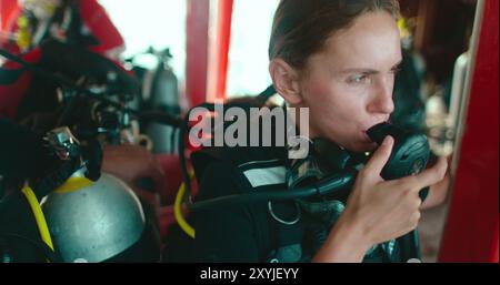 Frau bereitet sich auf das Tauchen auf einem Boot in thailand vor und überprüft ihre Ausrüstung sorgfältig, bevor sie ins Meer taucht Stockfoto