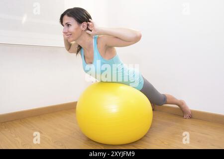 Frau, die im Fitnessstudio mit einem Trainingsball trainiert. Pilates Frau, die im Fitnessraum mit Fitnessball Übungen macht Stockfoto