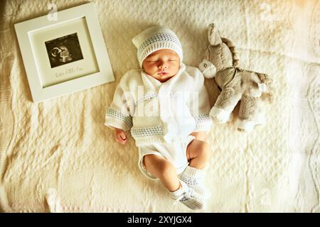 Teddybär, Neugeborenes und Baby im Bett zum Schlafen, Nickerchen oder Entspannen im Kinderzimmer mit Ultraschall. Niedliches Plüschtier und Junge, der mit ihm liegt Stockfoto