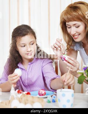 Glückliche Mutter und Tochter malen Ostereier Stockfoto