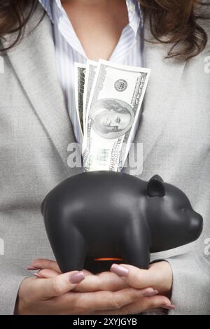 Geschäftsfrau, die die Sparkasse und die Dollarscheine in den Händen hält Stockfoto