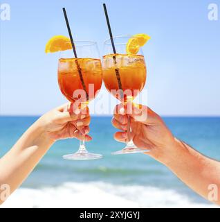 Zwei cocktail Gläser in der Hand auf das Meer im Hintergrund. Sommer Urlaub Konzept Stockfoto