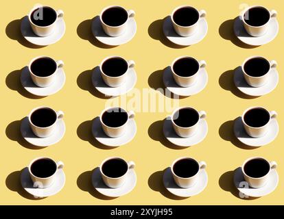 Muster der weißen Tasse und Unterteller des schwarzen Espresso-Kaffees von oben mit Schatten der Sonne auf beigem Terrakotta-Hintergrund. Stockfoto