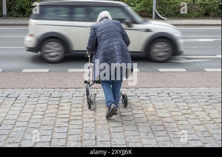 Ältere Frau mit Rollator will die Straße überqueren, vor ihr ein vorbeifahrendes Auto, Erlangen, Bayern, Deutschland, Europa Stockfoto