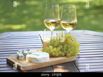 Verschiedene Arten von Käse, Weintrauben und zwei Gläser Weißwein Stockfoto