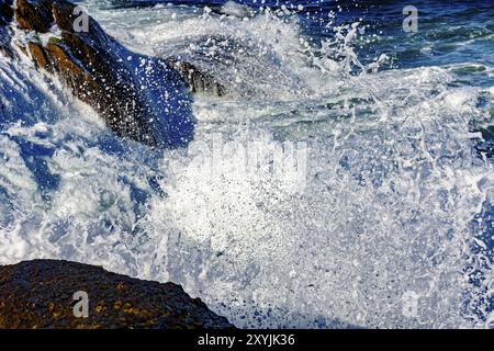 Details zu Wellenbrechen über Steinen mit Schaum, Wassertropfen und Spritzer Stockfoto