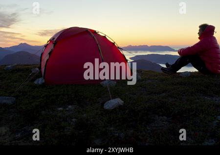 Wanderer sitzt auf einem Berggipfel neben seinem Zelt mit Blick auf den Moldefjord und die Nordsee, Moere und Romsdal Fylke, Vestland, Norwegen, 2. September Stockfoto