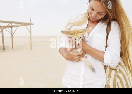 Junge Frau, die während des Reisens in der Sahara Fennec Fuchs in ihren Händen hält Stockfoto