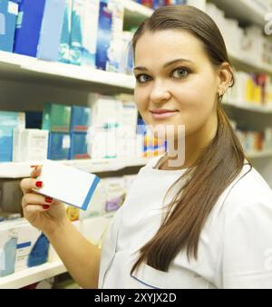 Junge Apothekerin zeigt Medizin-Box bei Apotheke Zähler Stockfoto