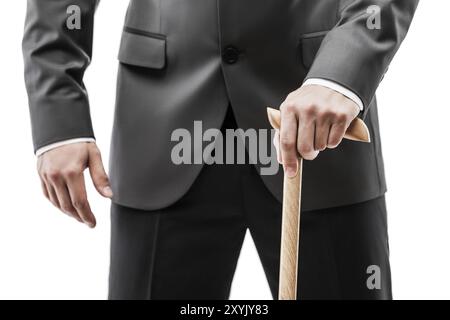 Geschäftsmann in schwarzer Anzughand, der weiß isoliert einen Gehstock aus Holz hält Stockfoto
