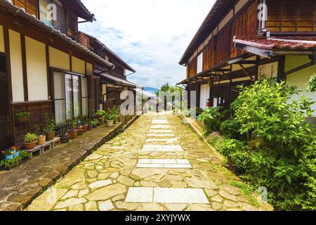 Wunderschön restaurierte traditionelle Holzhäuser säumen die Seiten eines Steinpfades auf dem alten Nakasendo-Weg tagsüber in Magome, Kiso Valley, Ja Stockfoto