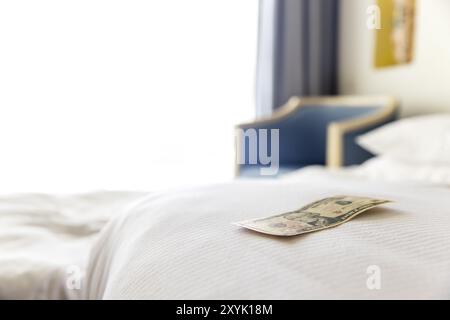 Traditionelle Tipps liegen auf der Bettecke im Hotelzimmer. Dollar- oder Euro-Trinkgeld, um dem Zimmerreiniger für den guten Service zu danken. Dankbarer Urlaub Stockfoto