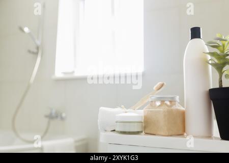 Waschbecken und Dusche im weißen Badezimmer mit Badaccessoires. Reinigungskonzept des Hotels. Haushaltskonzept. Shampoo, Körperpeeling, Creme, Zahnbürste, Handtuch Stockfoto