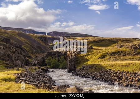 Weißer Fluss, der durch vulkanisches Gestein bei Hengifoss in Island fließt Stockfoto