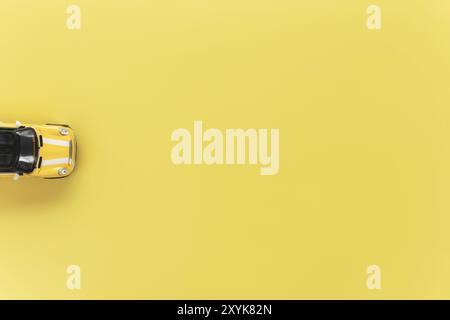 Autovermietung, Reise, Reise oder Wochenend-Aktivität Konzept flach lag mit gelben kleinen Spielzeug Cabriolet Auto auf gelbem Hintergrund Stockfoto
