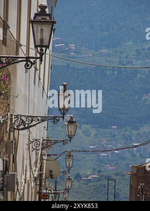 Eine Reihe von Laternen hängt über einer engen Gasse mit Blick auf die fernen Berge im Hintergrund, palermo, sizilien, mittelmeer, italien Stockfoto